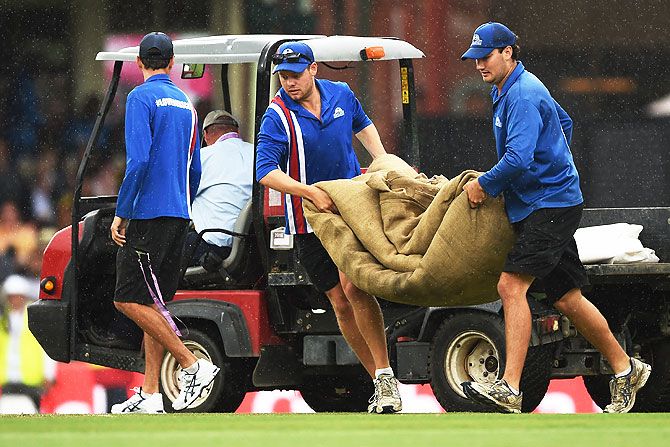 Groundsmen bring the covers on as rain delays play on Day 2 of the third Test match between Australia and the West Indies at Sydney Cricket Ground in Sydney on Monday