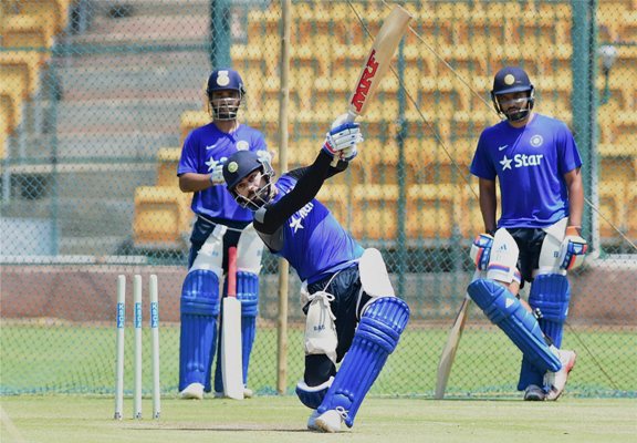 India's Virat Kohli bats in the nets as Ajinkya Rahane and Rohit Sharma watch during a training session 