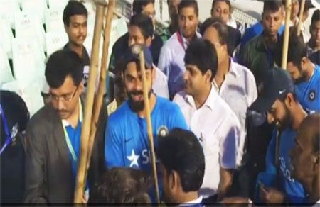 A video grab of India's captain Virat Kohli and teammate Ajinkya Rahane (right) standing with brooms after day's play on Day 3 at the Eden Gardens in Kolkata on Sunday