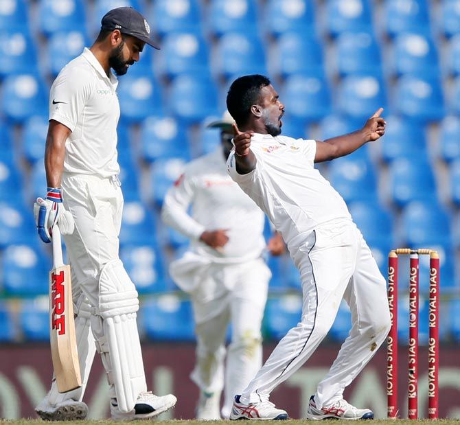 Malinda Pushpakumara, right, celebrates after taking the wicket of Ajinkya Rahane as Virat Kohli looks on during Day 1 of the 3rd Test played in Colombo, earlier in August 