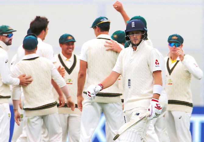 Australian players celebrate as England's captain Joe Root walks off the ground after being dismissed on the third day of the second Ashes cricket Test match at the Adelaide Oval