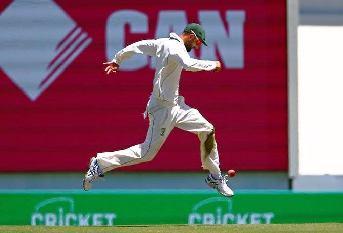 Nathan Lyon stops the ball from racing to the boundary