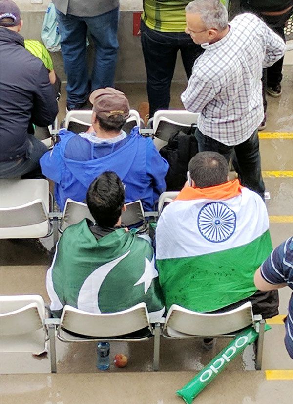 An Indian and Pakistani supporter watch the proceedings together