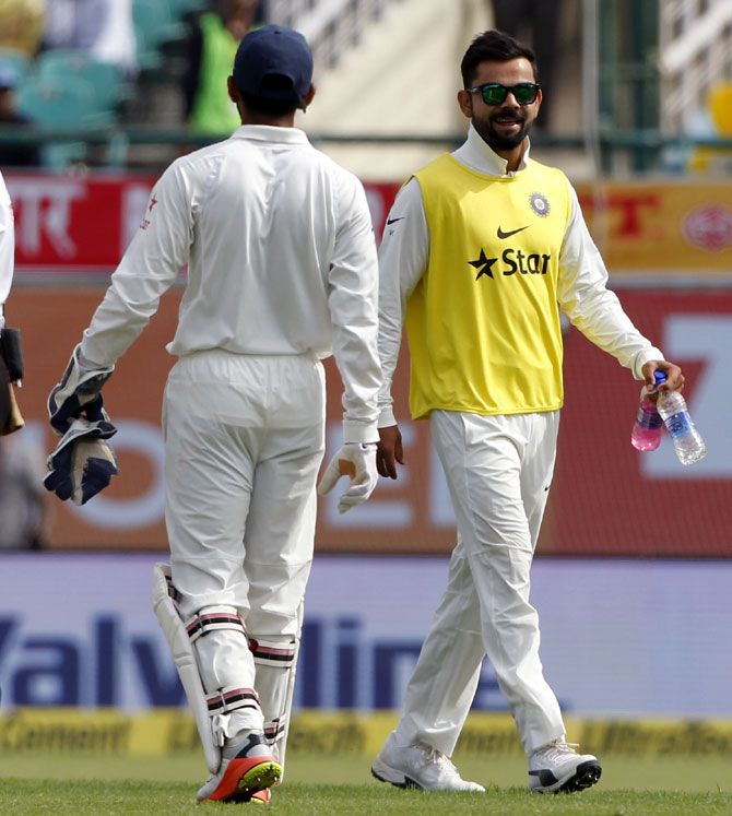 Virat Kohli brings drinks for his teammates on Day 1 of the 4th Test in Dharamsala on Saturday