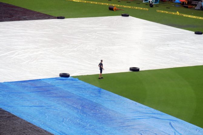 A New Zealand Cricket supporting staff takes a look at the ground which was covered owing to rain on Monday, ahead of their third and final T20 match against India at Thiruvananthapuram