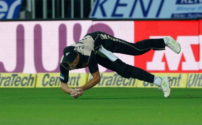 Mitchell Santner dives forward to complete a catch to dismiss Rohit Sharma