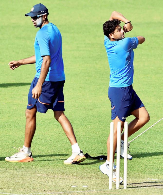 Indian chinaman bowler Kuldeep Yadav rolls his arm over as Ravichandran Ashwin looks on during a training session at Eden Garden in Kolkata on Monday