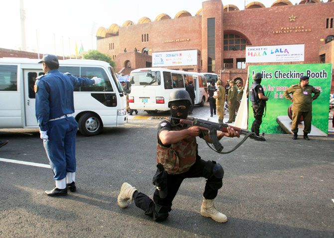 A member of the police elite force guards busses carrying cricket teams to Gaddafi Cricket Stadium for practice ahead of the World XI cricket series in Lahore on Monday