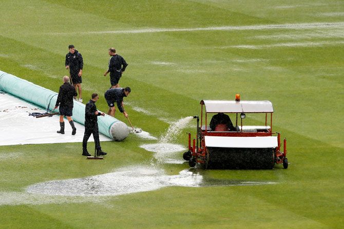 Groundsman work on the pitch during a rain delay 