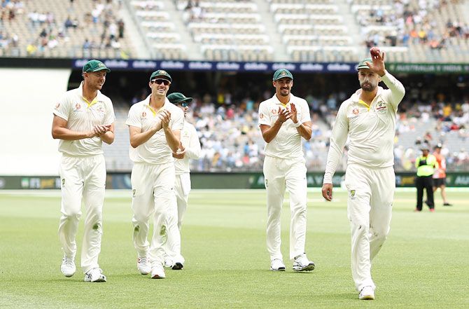 Australia's Nathan Lyon raises the ball aloft after claiming his fifth wicket at the end of India's first innings