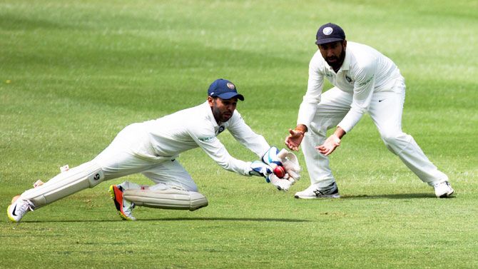 India's Parthiv Patel takes a catch to dismiss South Africa's Dean Elgar as Pujara looks on