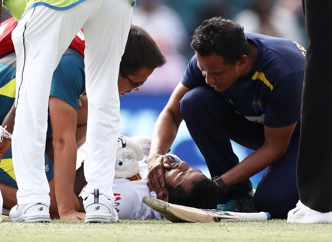 Sri Lanka's Dimuth Karunaratne receives medical attention after being struck by a delivery from Australia's Pat Cummins on Day 2 of the 2nd Test at Manuka Oval in Canberra on Saturday