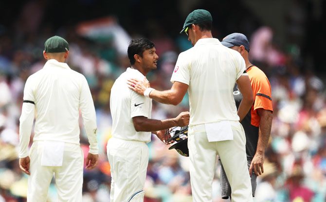 Mitchell Starc checks on Mayank Agarwal after he was struck on the helmet