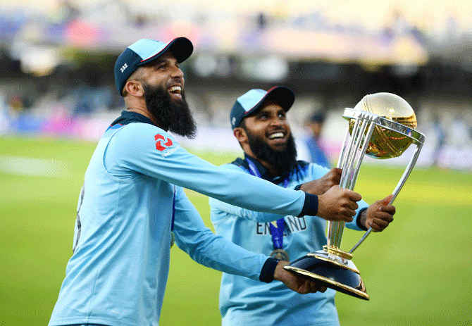 England's Moeen Ali and Adil Rashid parade the trophy after winning the ICC World Cup at Lord's Cricket Ground in London on Sunday
