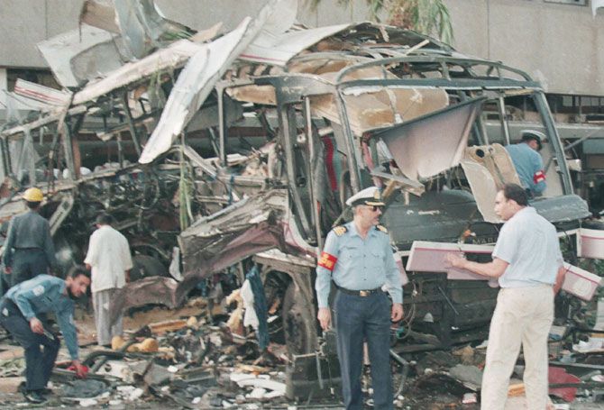Pakistan officials stand near the ruins of a bus after an explosion in Karachi on May 8, 2002. Nine French nationals were among the 11 dead in the explosion which also wounded at least 22 people after a bomb exploded near a hotel where the New Zealand cricket team were put up
