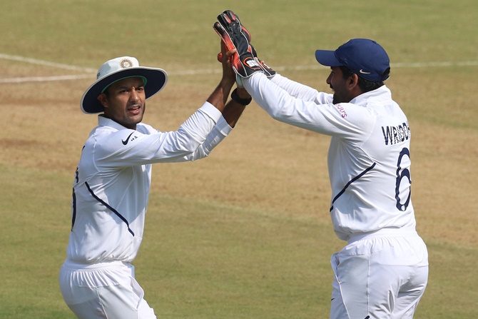 Mayank Agarwal and wicketkeeper Wriddhiman Saha celebrate the dismissal of Mohammad Mithun.