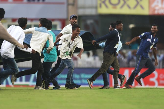 Ground staff run on to ground with the covers as sudden rain stops play on Day 1 of the 3rd Test between India and South Africa at the JSCA International Stadium Complex in Ranchi on Saturday