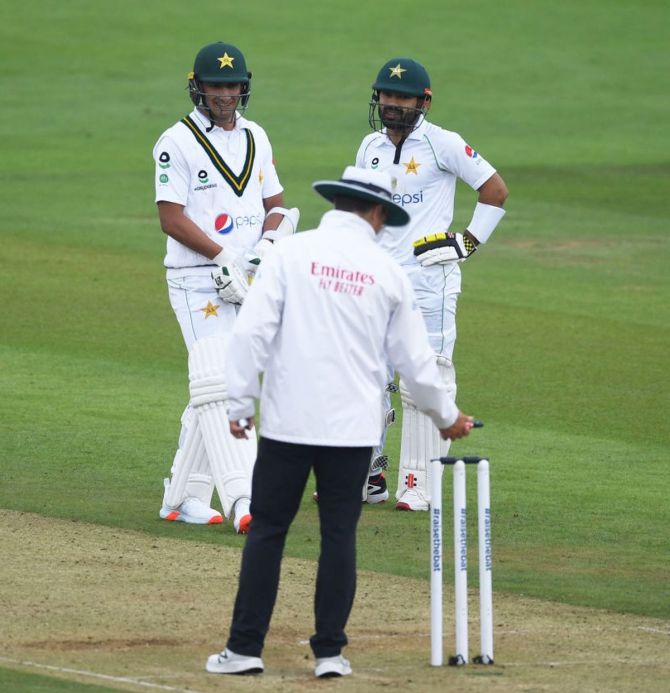 Pakistan batsmen Naseem Shah (L) and Mohammad Rizwan look on as Umpire Richard Kettleborough checks the light meter reading on Day Two of the 2nd #RaiseTheBat Test Match against England at the Ageas Bowl in Southampton on Friday. 