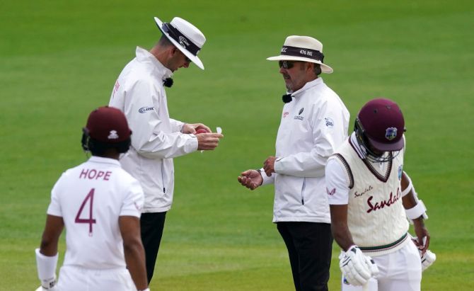 Umpires Michael Gough and Richard Illingworth sanitise the ball after England's Dom Sibley accidently uses saliva to it on Day 4 of the 2nd Test Match in the #RaiseTheBat Series between England and The West Indies at Emirates Old Trafford in Manchester on Sunday