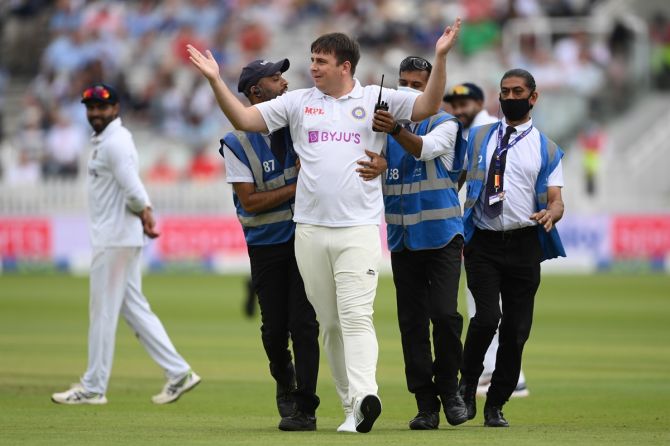 A pitch intruder is led away by security officials during Day 3 of the second India-England Test, at Lord's Cricket Ground, on Saturday.