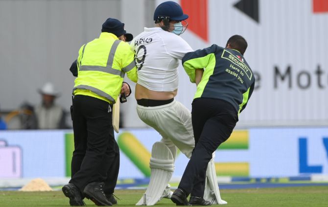 A pitch invader, dressed as a batsman, is escorted off the field during Day 3 of the third Test between England and India, at Emerald Headingley stadium in Leeds, on Friday.