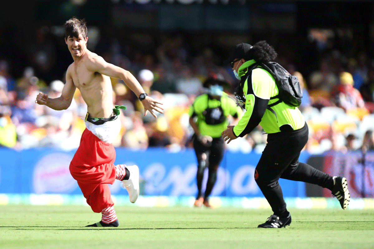 A pitch invader is chased by security. 
