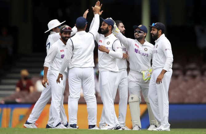 Cheteshwar Pujara celebrates with his India teammates after taking the catch of David Warner