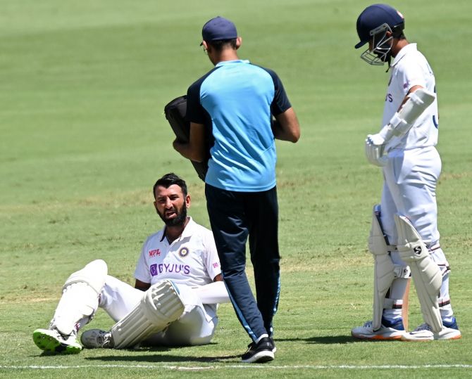 Cheteshwar Pujara receives medical attention after being struck on the hand by a delivery from Josh Hazlewood. 