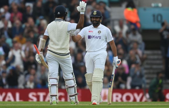 India's Rohit Sharma gets a high-five from Cheteshwar Pujara after completing his hundred.r  