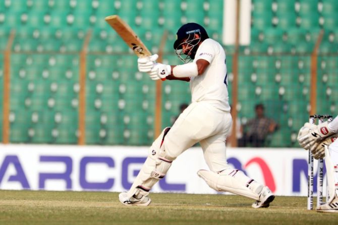 India's Cheteshwar Pujara hits runs watched on by England wicketkeeper Sam Billings