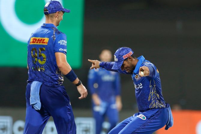 MI's Tilak Verma (right) celebrates with Dan Sams after taking a catch to dismiss KKR's Pat Cummins for a duck