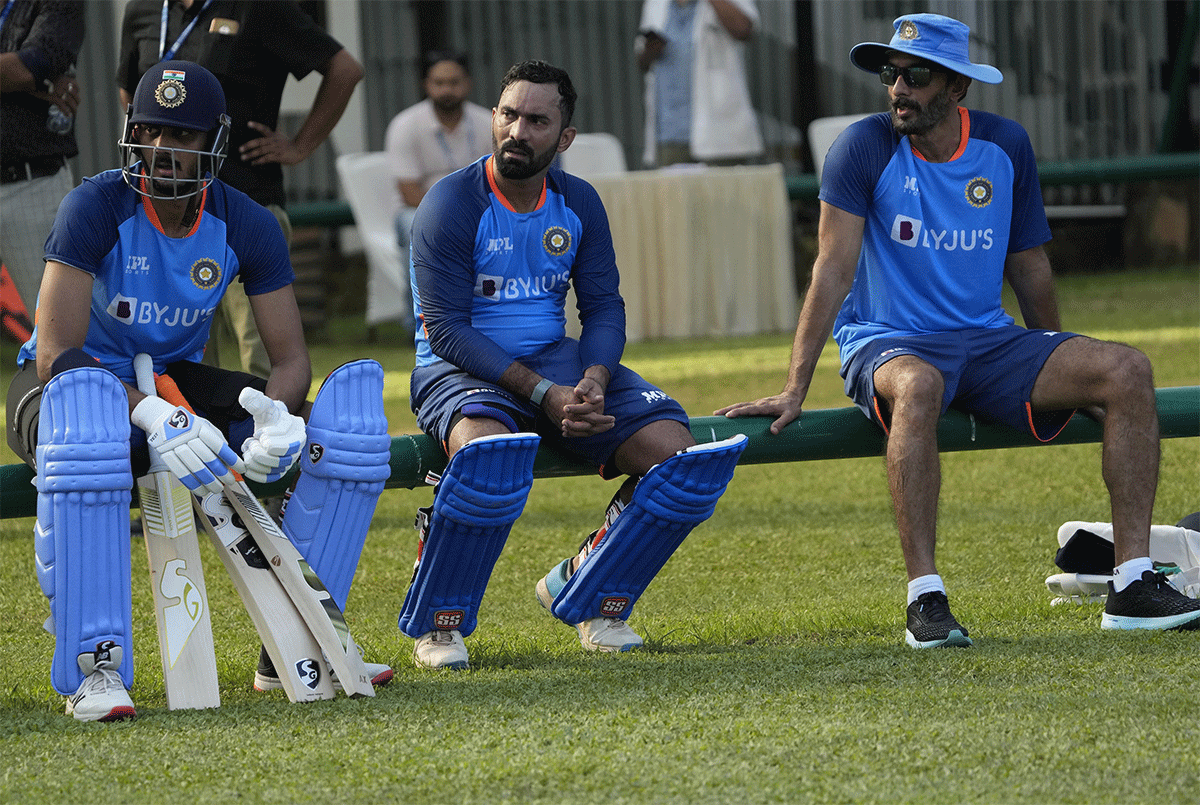 Axar Patel and Dinesh Karthik await their turn while batting coach Vikram Rathore looks on 