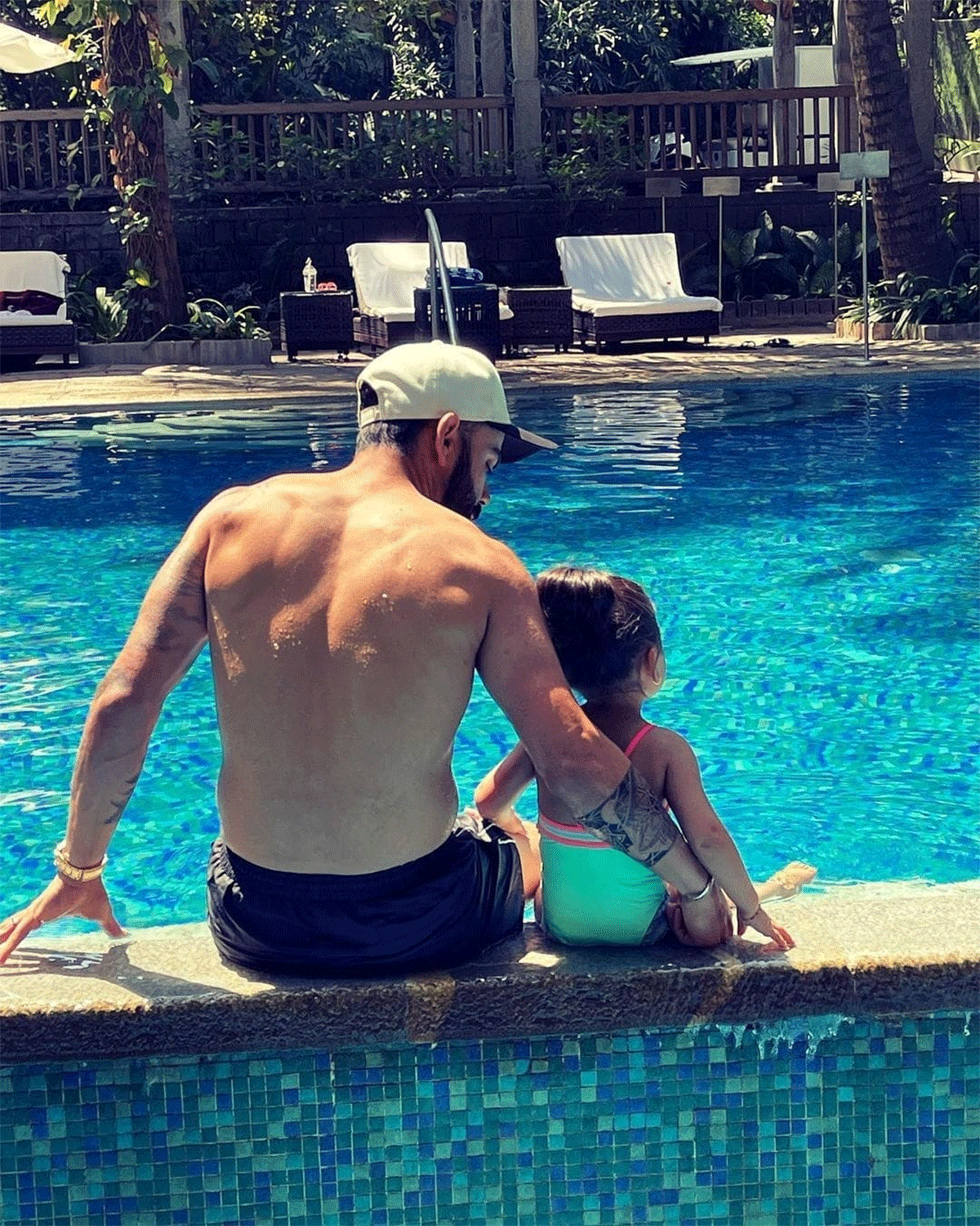Virat Kohli puts a caring arm around his daughter Vamika as they sit by the pool