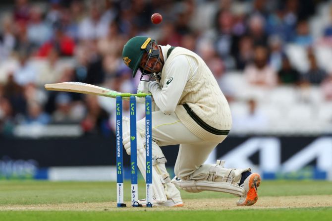 Australia's Usman Khawaja is hit on the back of the helmet by a delivery by England's Mark Wood