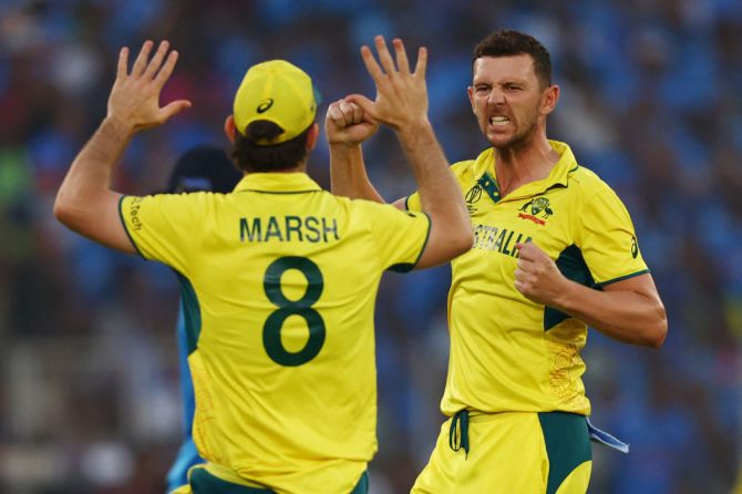 Australia's Josh Hazlewood celebrates with Mitchell Marsh after taking the wicket of India's Suryakumar Yadav, caught out by Josh Inglis