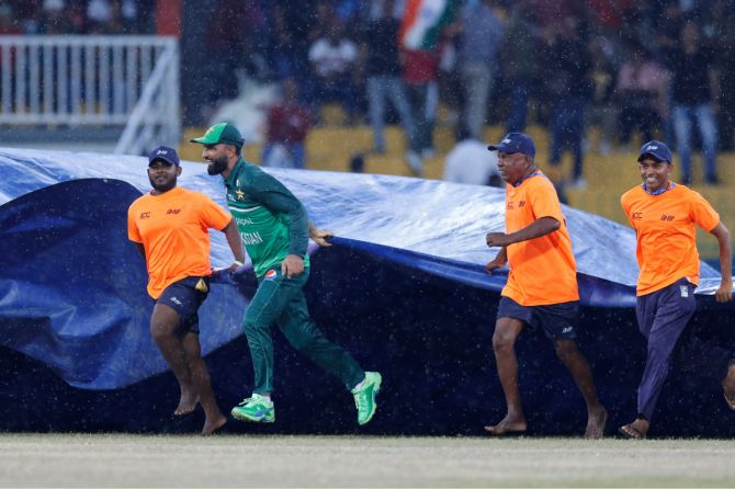 Pakistan batter Fakhar Zaman helps ground staff bring out the covers at the Premadasa Stadium in Colombo on Sunday