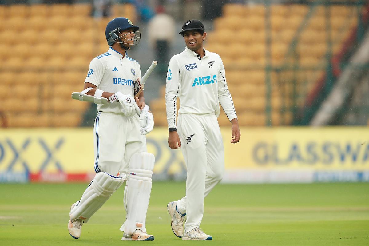 India's Yashasvi Jaiswal and New Zealand's Rachin Ravindra chat as they walk off the pitch as rain interrupts play 