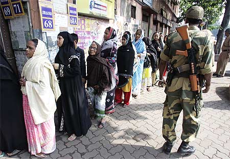 Citizens queue up to vote as a security personnel stands guard in Kolkata