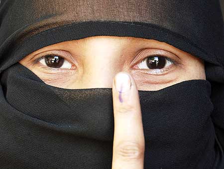 A Muslim woman voter shows her ink-marked finger after casting her ballot