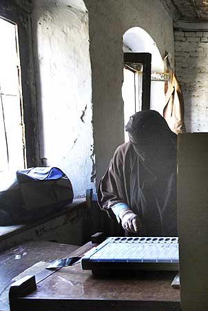 A veiled Kashmiri voter prepares to cast her vote