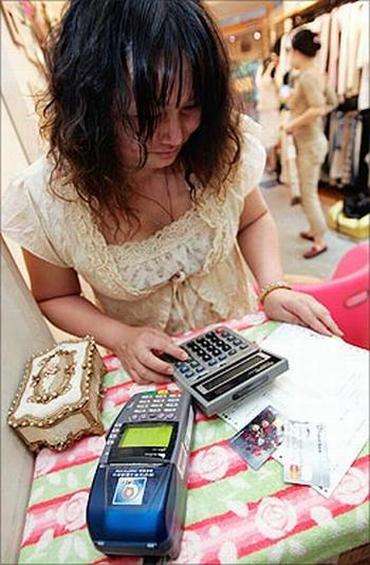 A shopkeeper calculates the amount of credit racked up at the end of the day after swiping credit cards in Taipei, Taiwan.