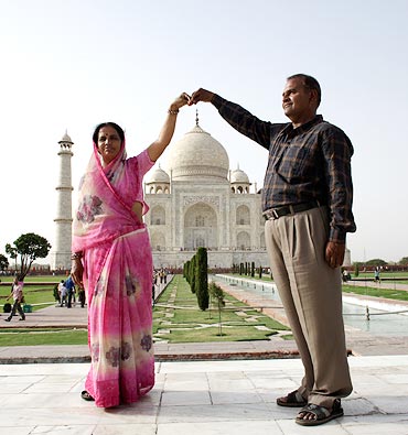 Tourists pose in front of the Taj Mahal in Agra