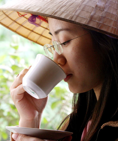 A Vietnamese girl drinks a cup of coffee in Hanoi December 8, 2004. Coffee prices eased on Tuesday in Vietnam, the world's top robusta producer and exporter, as the harvest hit its peak and as sellers moved to the sidelines after a sharp price drop snuffed out last week's rally, traders said.