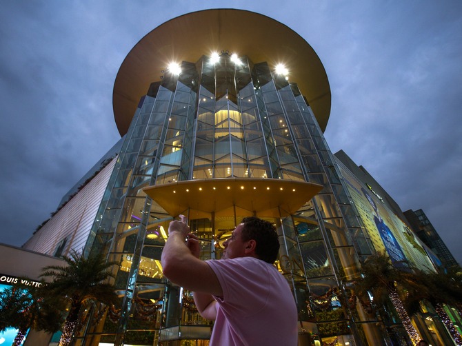 A tourist takes a photo in front of Siam Paragon Department Store in central Bangkok December 16, 2013. Bangkok's Siam Paragon shopping mall is the most popular location among Instagram users, and Bangkok the second most popular city this year, the network's blog announced.