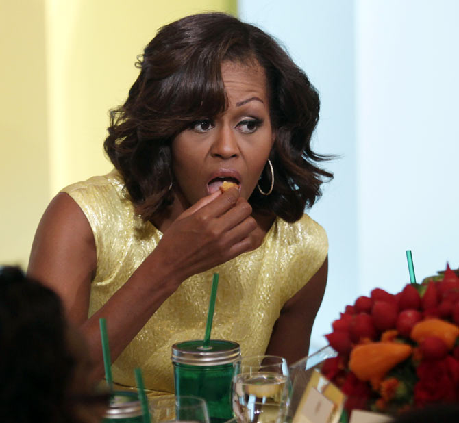U.S. First Lady Michelle Obama (L) eats as she hosts the second annual Kids' State Dinner, to honor the winners of a nationwide recipe challenge to promote healthy lunches, at the White House in Washington July 9, 2013.