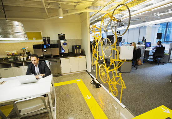 A Google employee works in the kitchen beside a structure made of recycled bicycles at the new Google office in Toronto