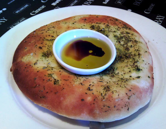 Focaccia bread topped with herbs and served with olive oil