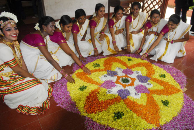 Young girls pose next to a Pookalam designed by them