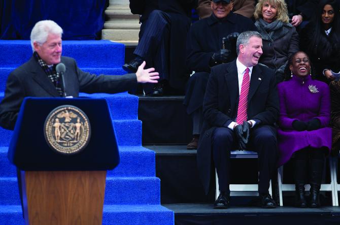 Ramya Ramana, sitting second row right, watches former US President Bill Clinton introduce New York City Mayor Bill de Blasio, sitting first row, second from right, with his wife Chirlane McCray in New York, January 1.