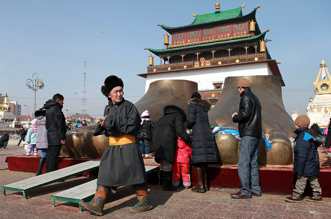 People offer donations in front of a feet-shaped statue at Gandan monastery of Ulan Bator, February 23, 2013. Mongolian people crowd to the monastery before the 15th day of the Mongolian New Year, as they believe having monks read old buddhist scripts for them could disperse bad luck and bring good fortune in the New Year.